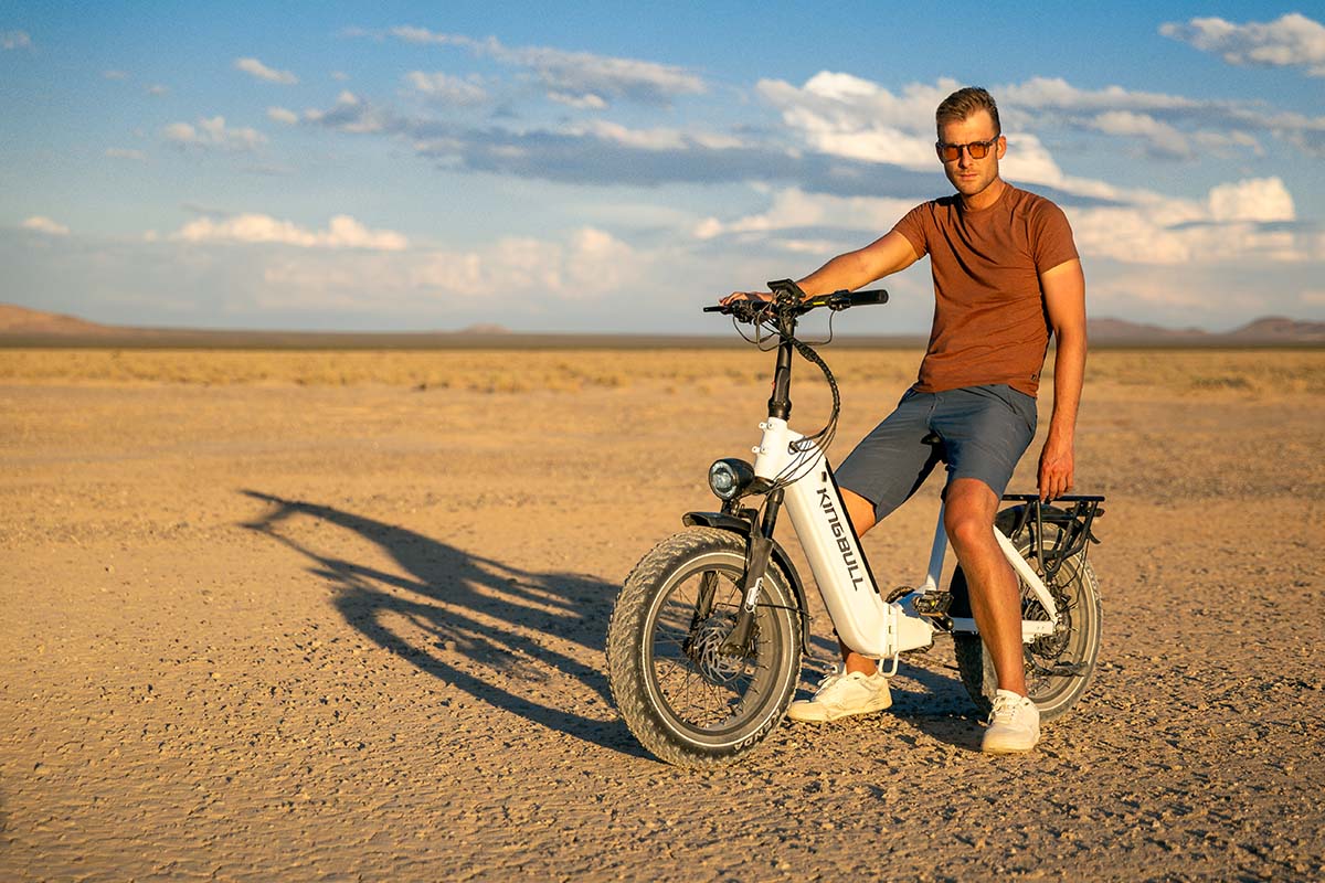 Rider seated on a white Kingbull Verve e-bike on a Mojave dry lake bed at golden hour, by Niaz Uddin