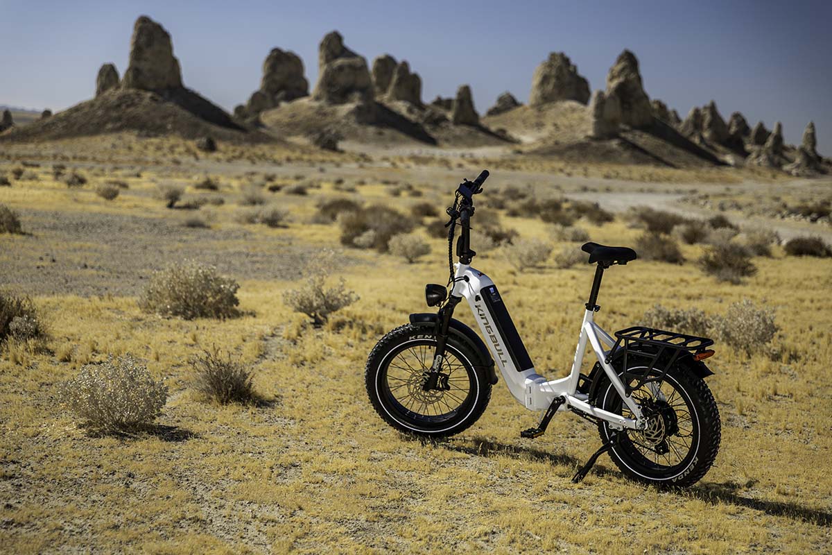 Wide view of a white Kingbull Verve e-bike in golden desert grass below the Trona Pinnacles, Mojave, by Niaz Uddin