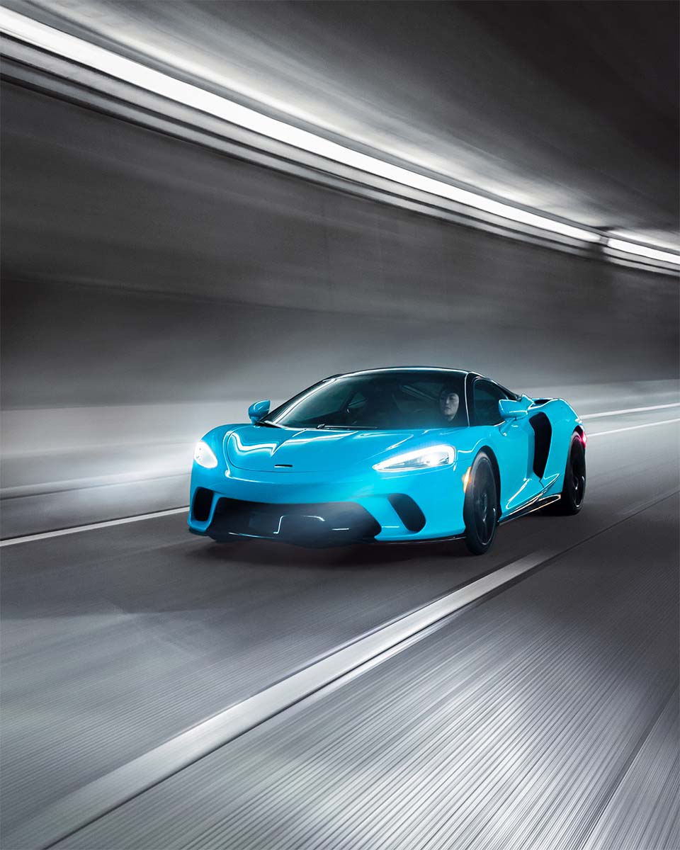 Cyan McLaren GT in motion through a tunnel with streaking light trails, by Niaz Uddin