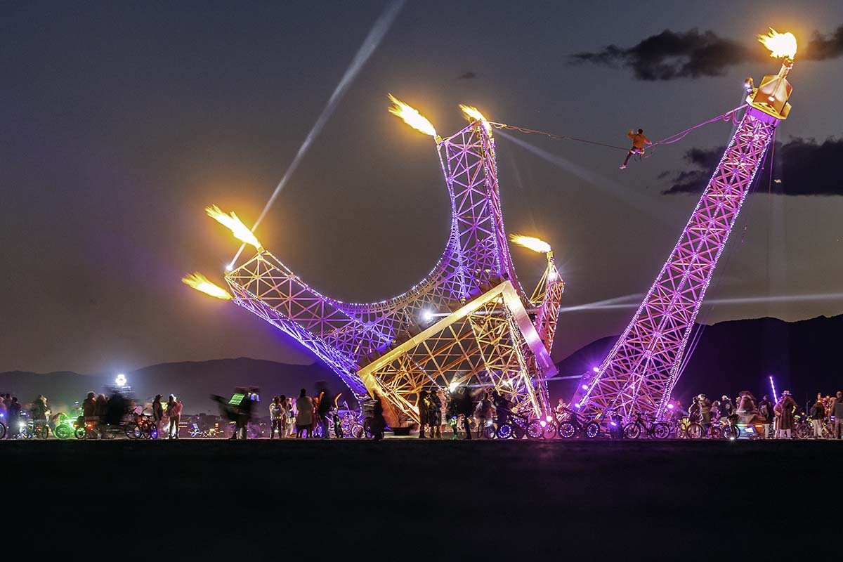 Fire art installation shaped like a collapsing Eiffel Tower shooting flames at night, Burning Man 2026, by Niaz Uddin