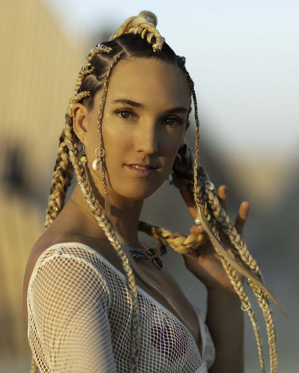 Portrait of Gloria Riechers with braided hair in warm evening light on the playa, Burning Man 2026, by Niaz Uddin