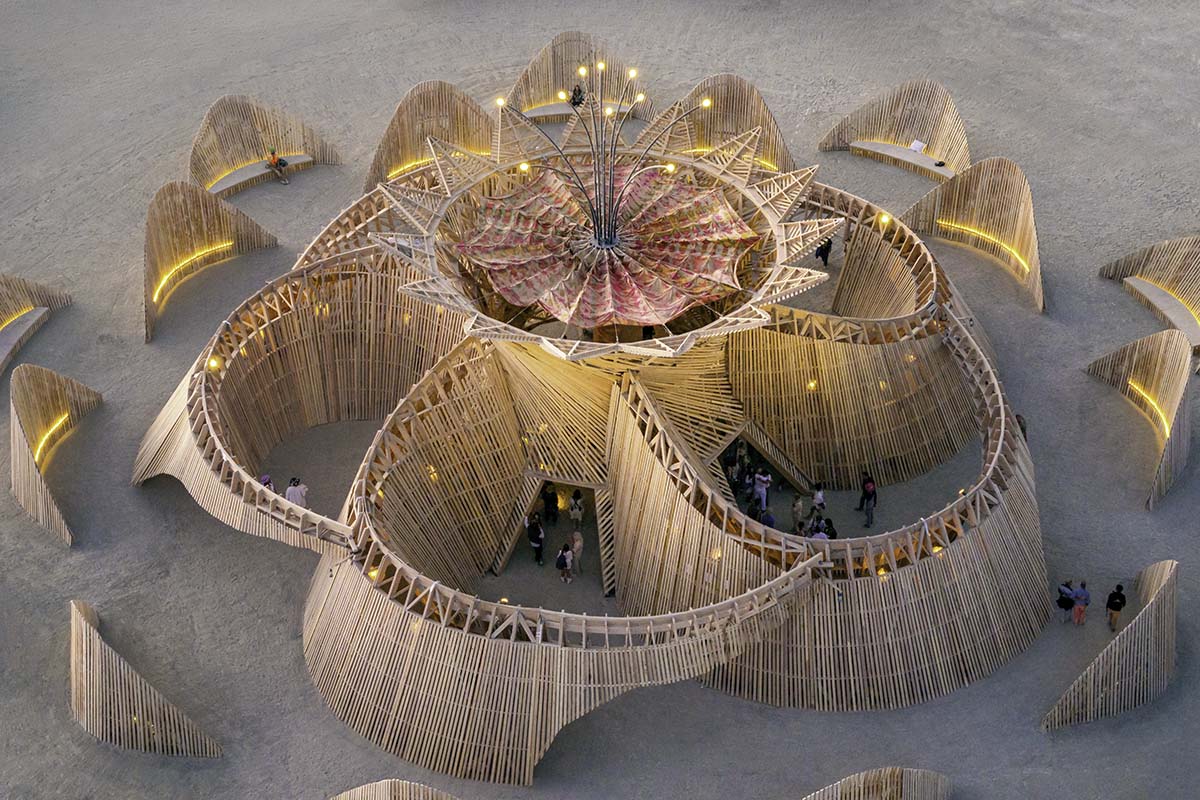 Aerial of the full 2026 Burning Man temple glowing at blue hour, its flower-shaped petals lit from within, by Niaz Uddin