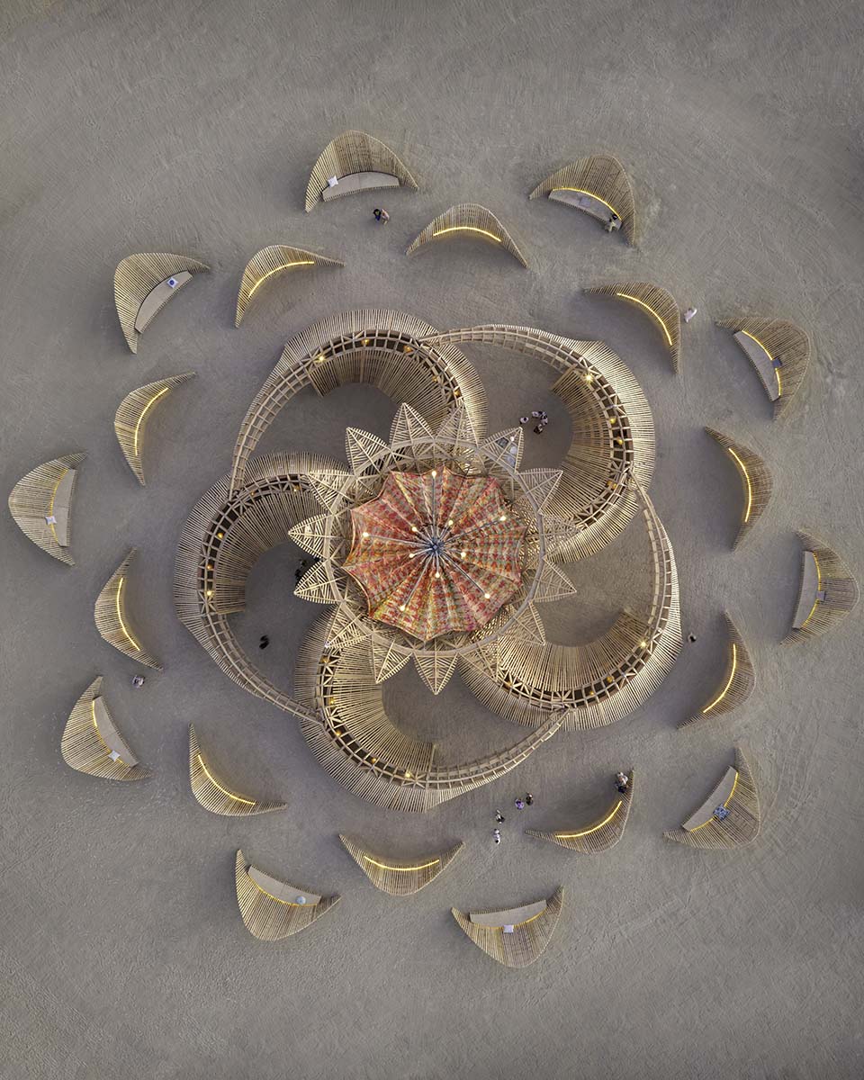 Vertical aerial of the 2026 Burning Man temple lit at blue hour, petals radiating across the playa, by Niaz Uddin