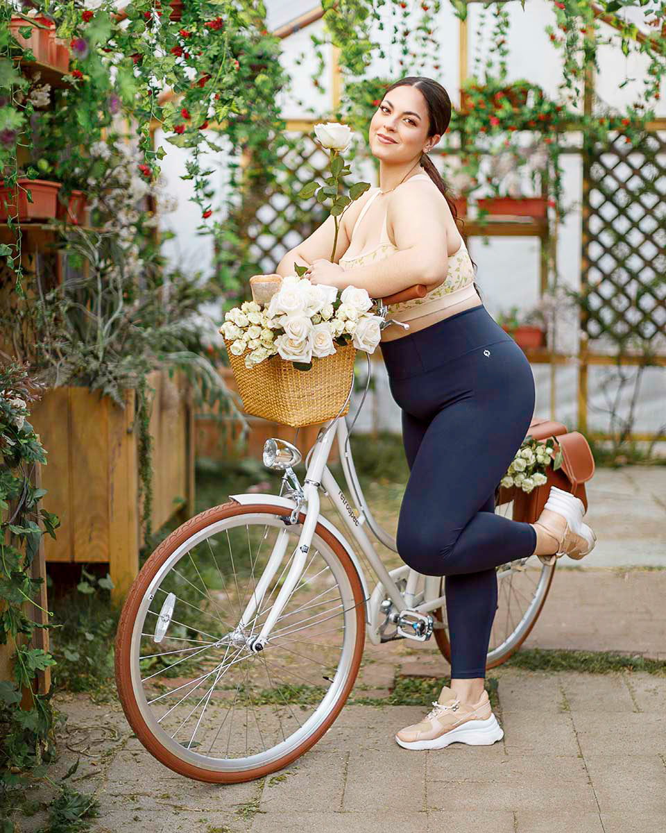 Model standing in a navy POPFLEX cutout romper framed by hanging ivy and flowers, by Niaz Uddin