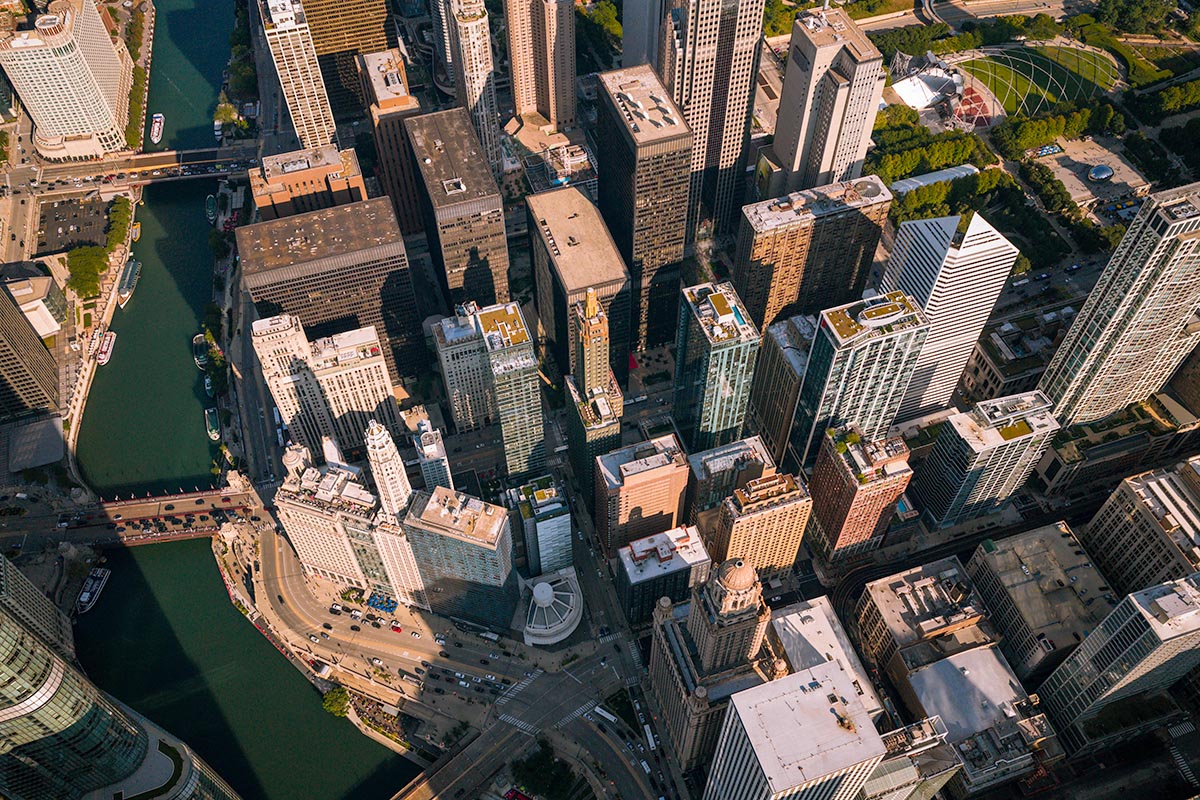 Golden-hour aerial of downtown Chicago with the Chicago River bend, the Wrigley Building, and Millennium Park, by Niaz Uddin