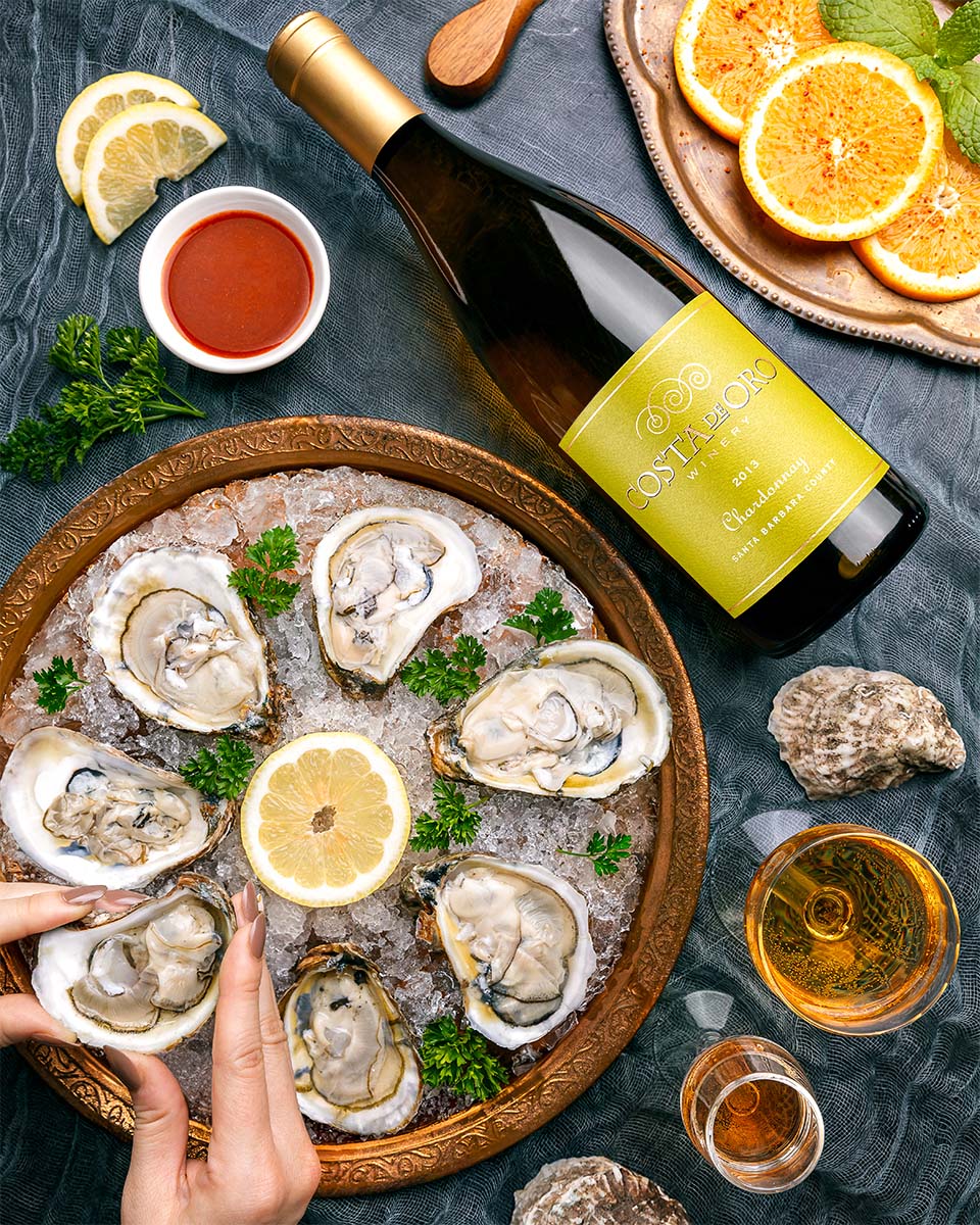 Costa de Oro Chardonnay beside a platter of fresh oysters on ice with lemon and citrus, by Niaz Uddin