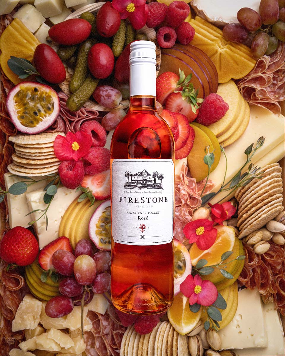 Firestone Vineyard Rosé resting on an abundant charcuterie board of cheese, fruit, crackers, and cured meats, by Niaz Uddin
