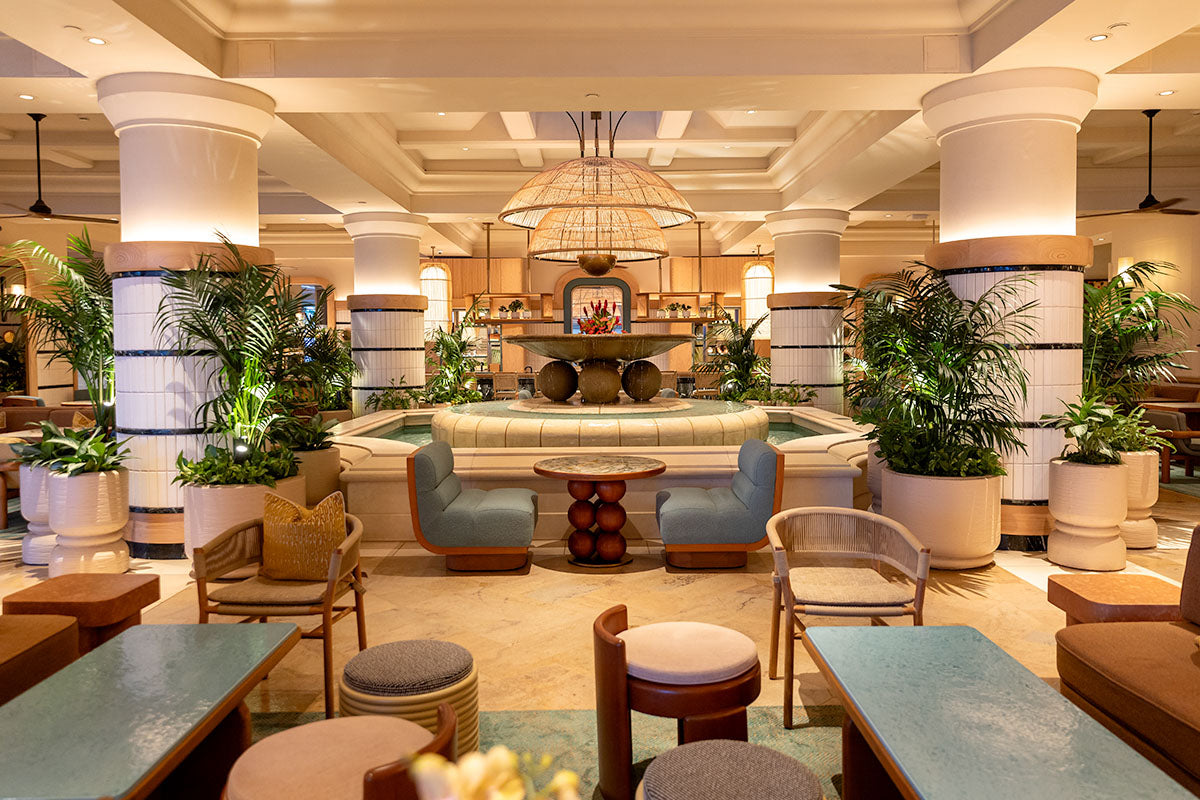 Open-air lobby lounge at Four Seasons Resort Maui with a central fountain, rattan dome pendants, and palms, by Niaz Uddin