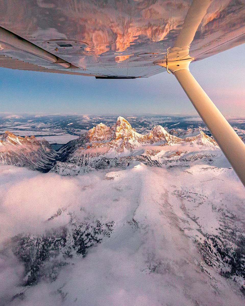 Grand Teton mountains at winter sunrise seen past an airplane wing