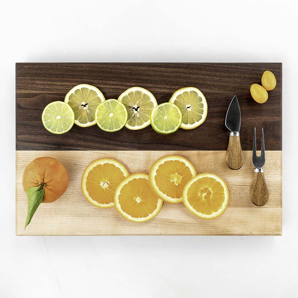 Sliced citrus and oranges with a cheese knife and fork on a two-tone Hawker Woodcraft walnut and maple charcuterie board, by Niaz Uddin