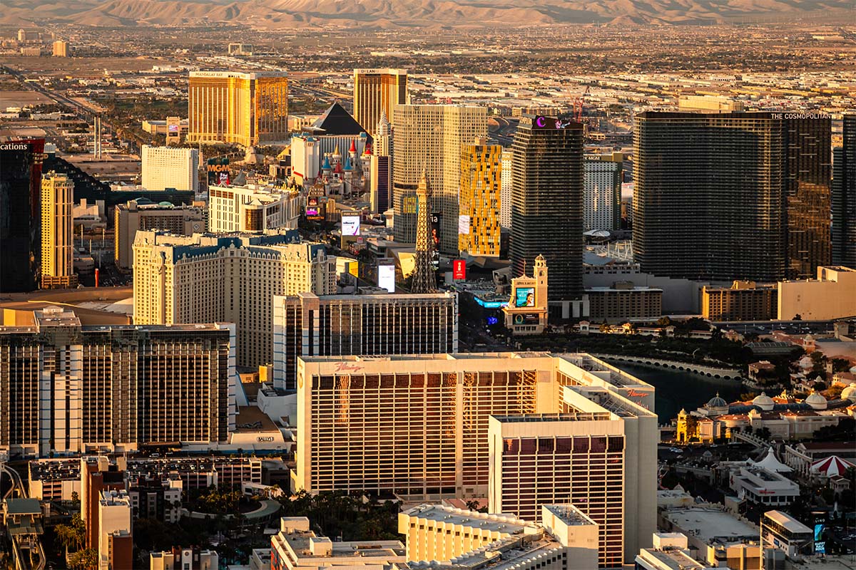 Golden-hour aerial looking south down the Las Vegas Strip over the Flamingo toward MGM Grand and Mandalay Bay, with the mountains beyond, by Niaz Uddin