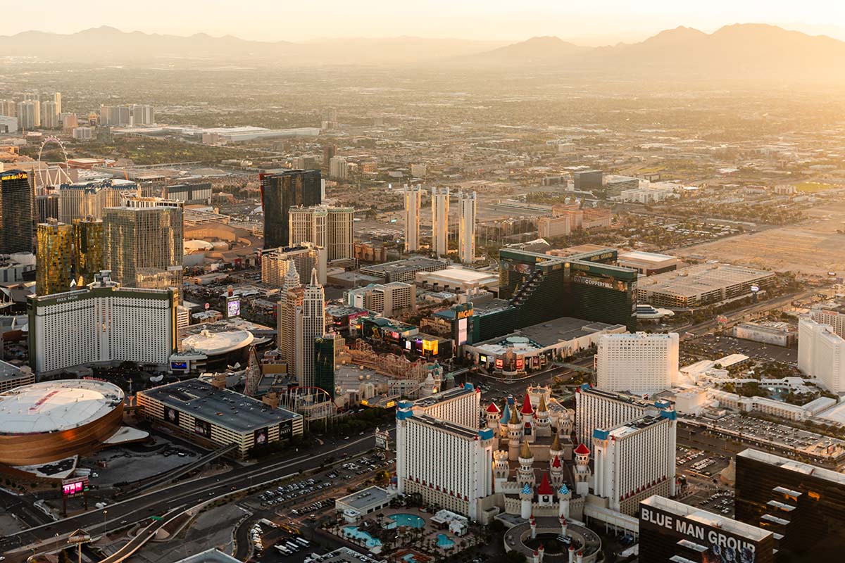 Golden-hour aerial of the south Las Vegas Strip with Excalibur, New York-New York, T-Mobile Arena, and MGM Grand in warm sunset light, by Niaz Uddin