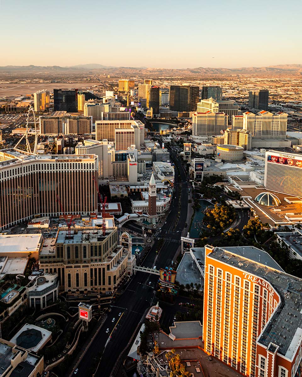 Vertical golden-hour aerial of the Las Vegas Strip with Treasure Island in the foreground and the Venetian and Mirage along the boulevard, by Niaz Uddin