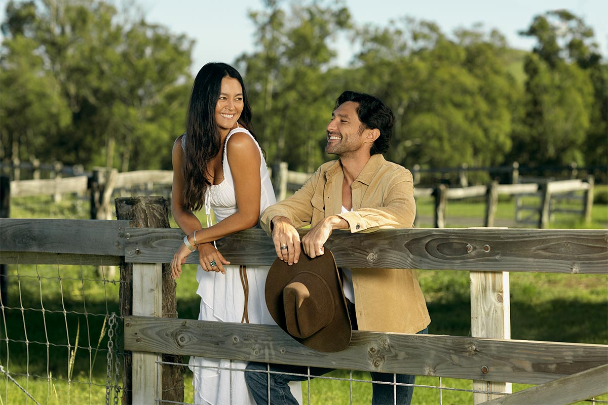 Couple laughing together at a wooden ranch fence at Makena Beach Club, Maui, by Niaz Uddin