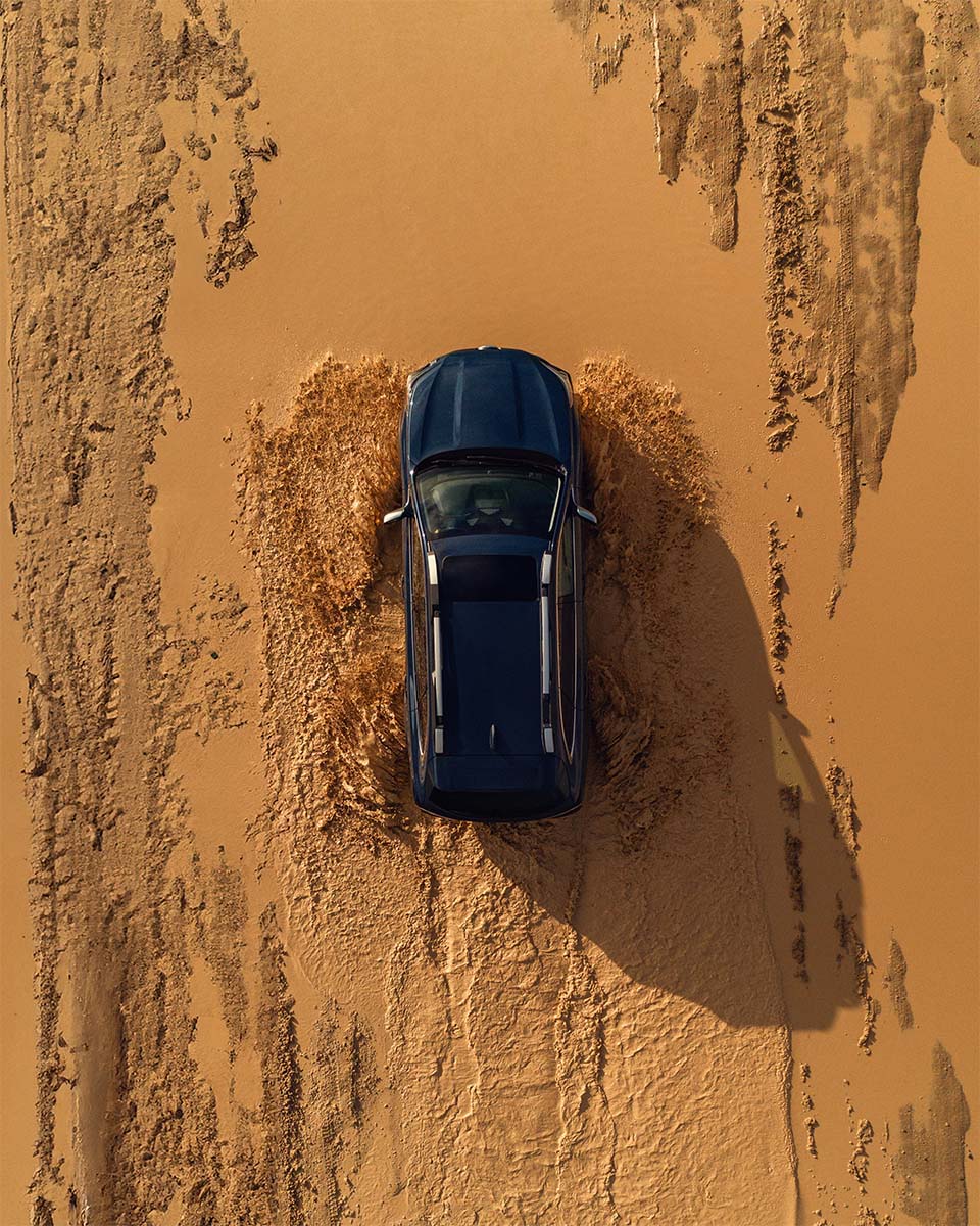 Aerial drone view of a Subaru Outback off-roading through desert mud, by Niaz Uddin