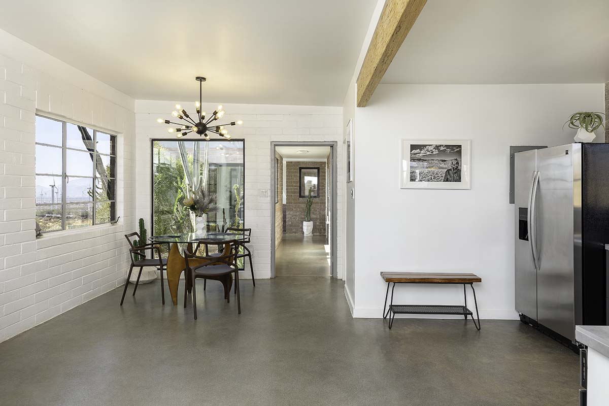 Dining room with a sputnik chandelier and white brick walls in the Palm Springs dome house, by Niaz Uddin