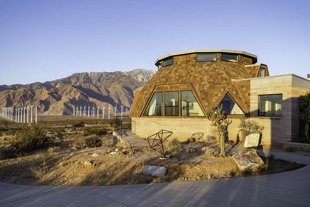 Exterior of the geodesic dome house at golden hour with the San Jacinto mountains and a wind farm behind, near Palm Springs, by Niaz Uddin