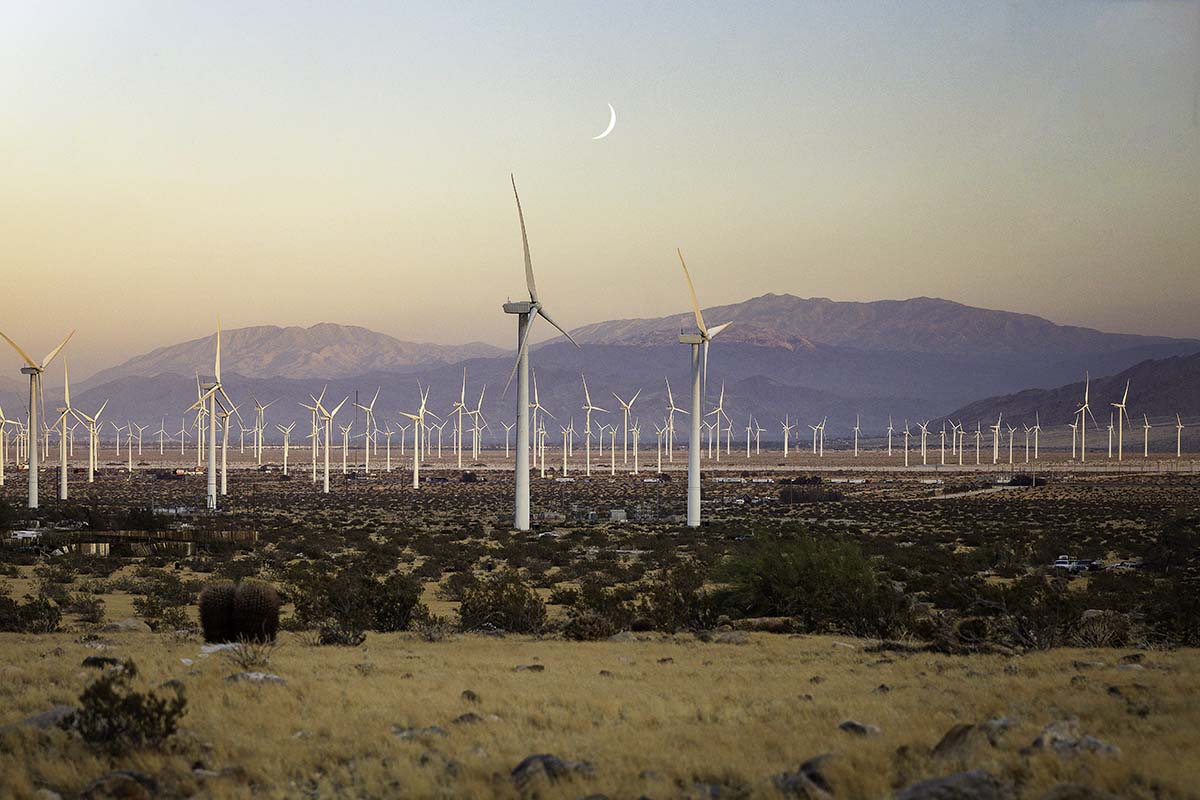 Wind turbines of the San Gorgonio Pass wind farm at dusk under a crescent moon, near Palm Springs, by Niaz Uddin