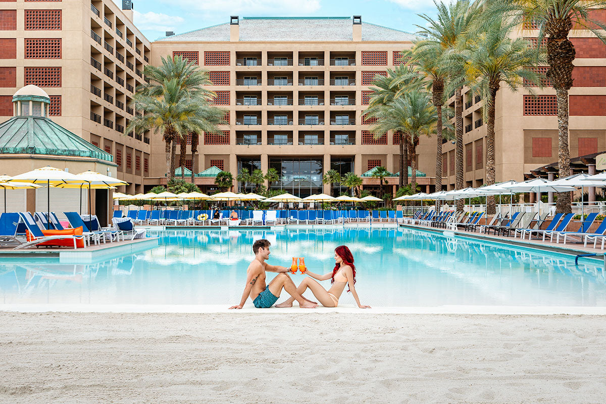Couple toasting cocktails at the edge of the beach-entry pool at Renaissance Esmeralda Resort & Spa in Indian Wells