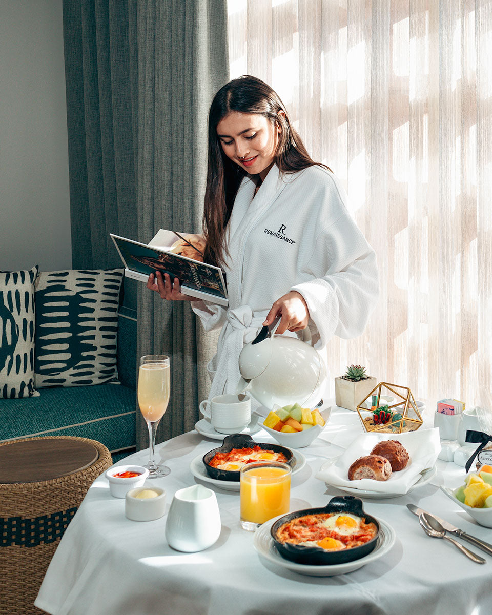 Guest in a Renaissance robe with in-room dining breakfast at Renaissance Esmeralda Resort & Spa in Indian Wells