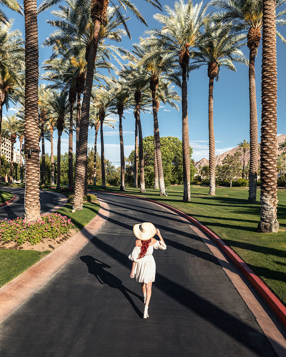 Woman walking down the palm-lined entrance drive at Renaissance Esmeralda Resort & Spa in Indian Wells