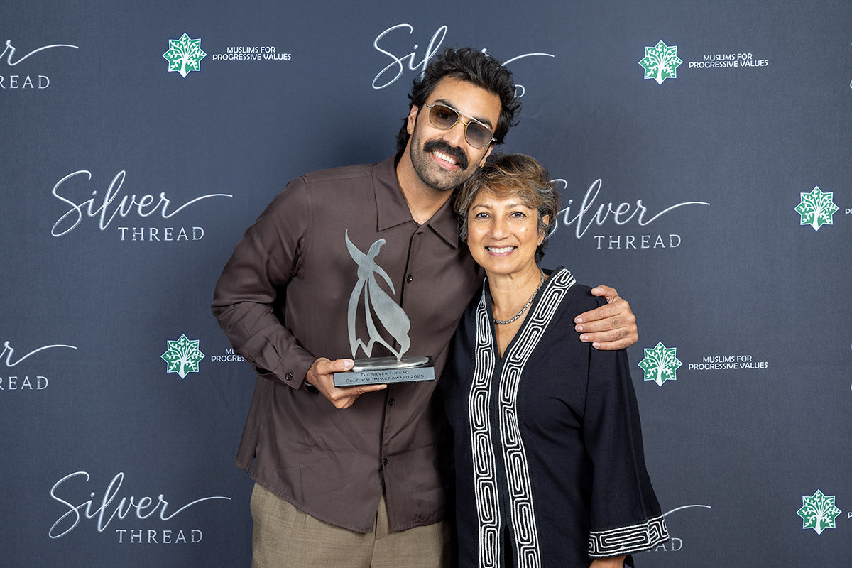 Honoree holding the Silver Thread Cultural Impact Award beside a presenter at the step-and-repeat