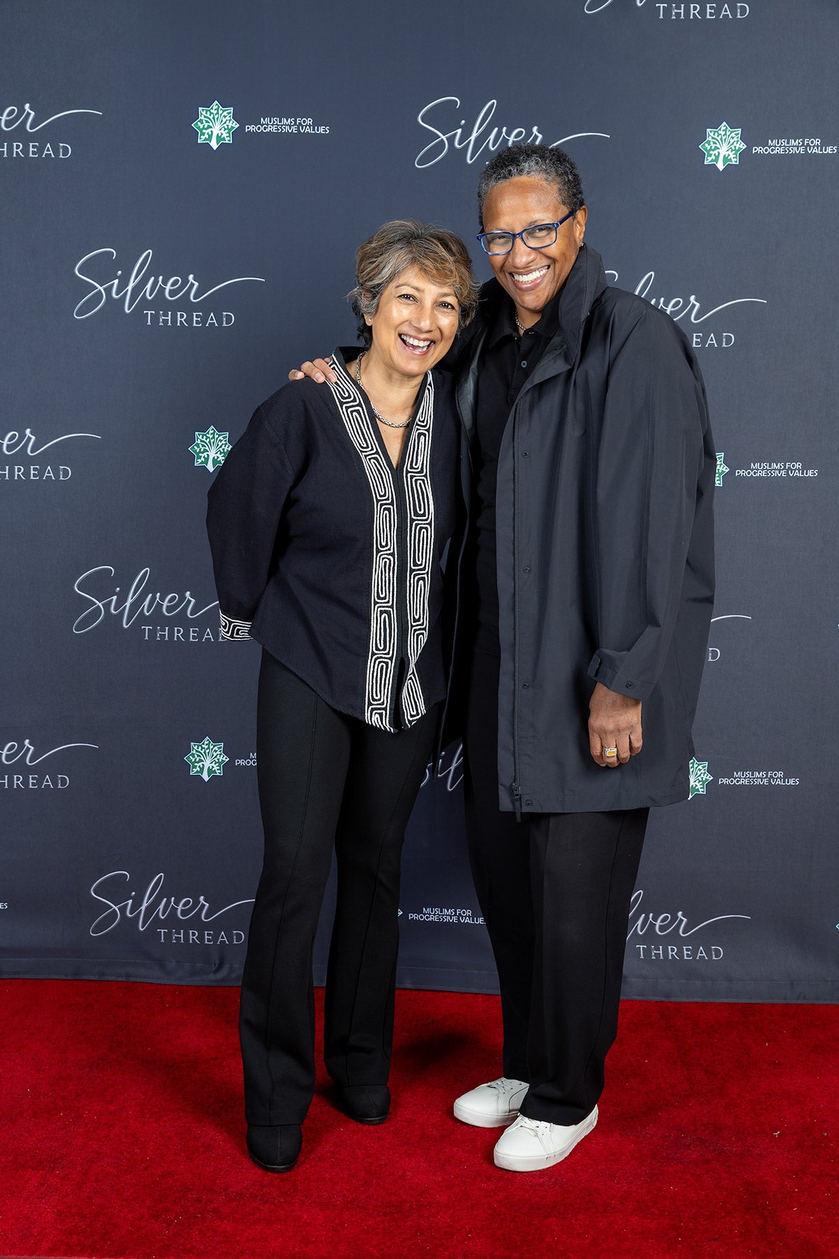 Two guests embracing at the Silver Thread step-and-repeat