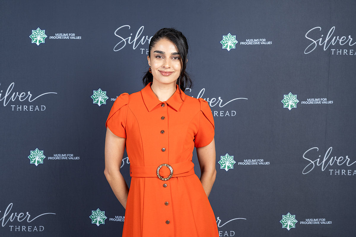 A guest in an orange belted dress on the Silver Thread red carpet