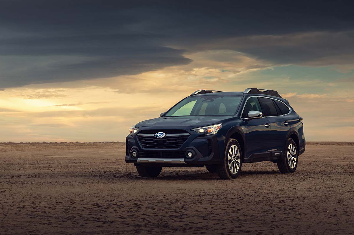 Blue Subaru Outback parked on rocky desert terrain under a stormy sky, by Niaz Uddin