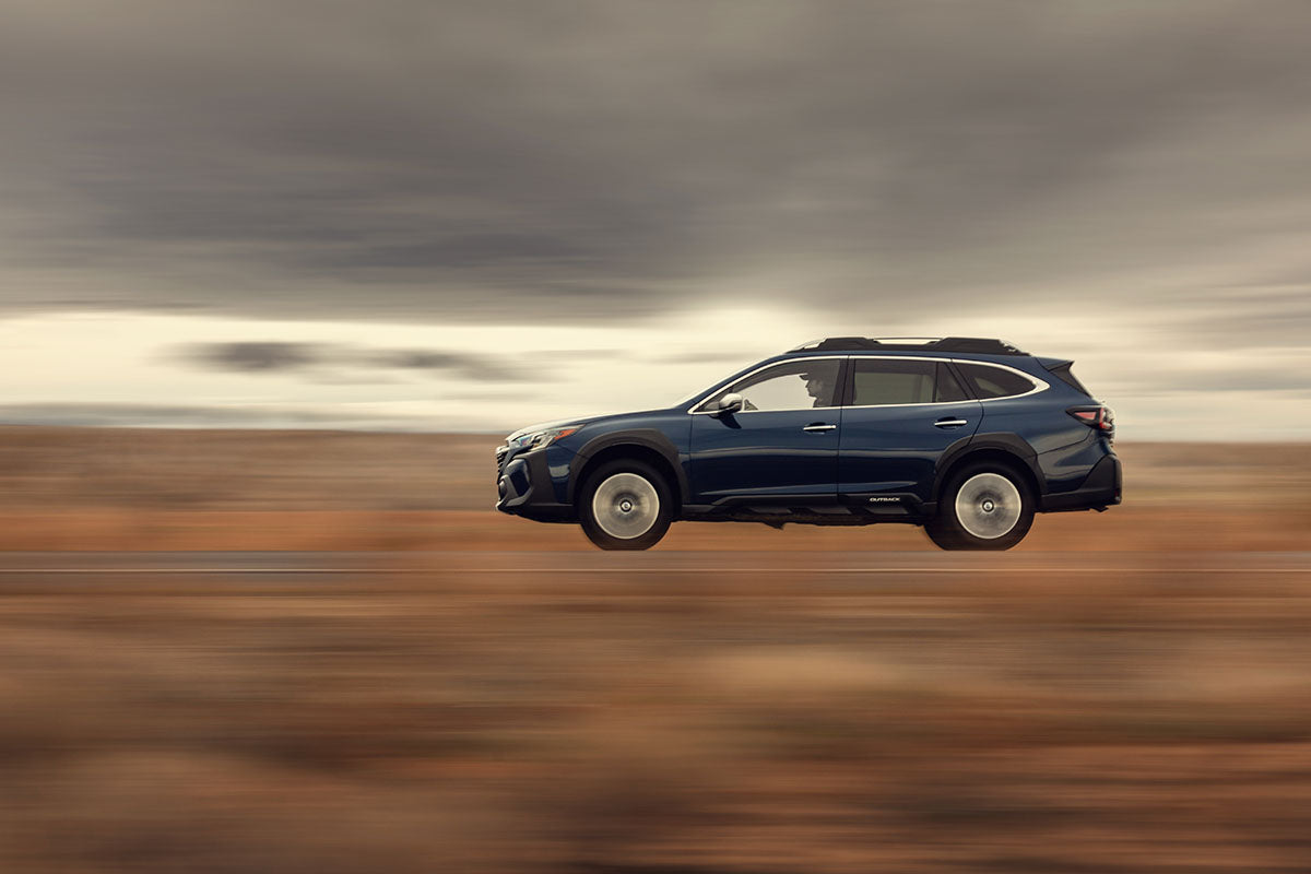 Blue Subaru Outback in motion, panning side-profile blur across the desert, by Niaz Uddin